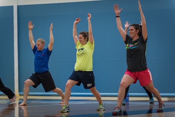 A group of people do yoga moves in a gym
