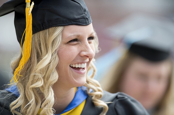 A Lakeland University graduate smiling with cap and gown.