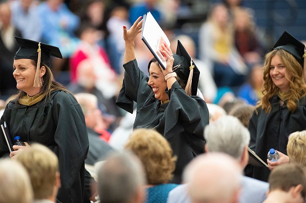 Lakeland University graduate with arms in the air.