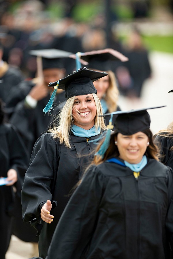 Lakeland graduates smiling walking to graduation ceremony.