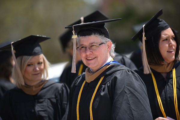 Lakeland graduate student smiles on the way to graduation ceremony